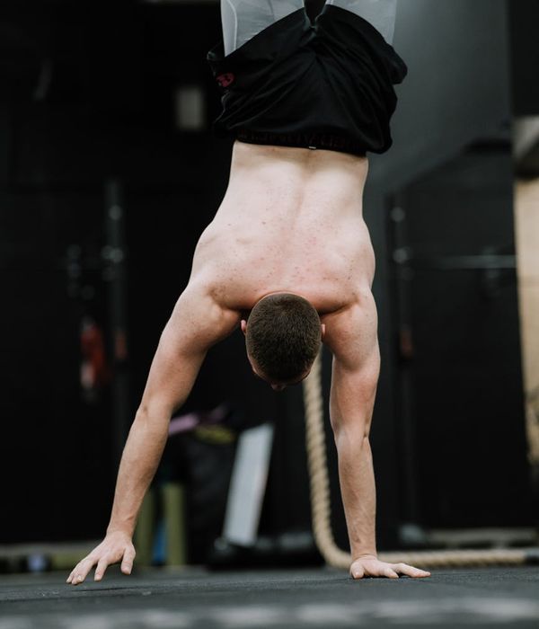 Man performing a challenging core stability exercise in a dark, focused environment.